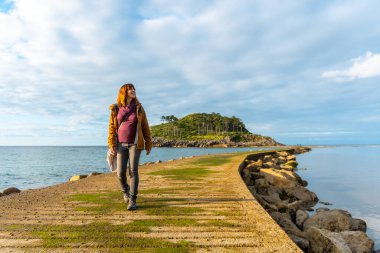 Lekeitio, Bask Bölgesi 'ndeki Isuntza sahilinden San Nicolas Adası' na giden yaya köprüsündeki genç bir turist. Biscay Körfezi. İspanya
