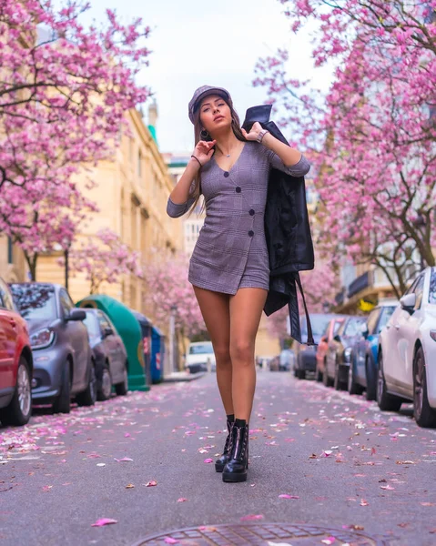 城市里街上的风格 黑发白种人姑娘穿着皮夹克走在城市里 春天开着花的树 — 图库照片