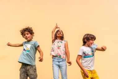 Children celebrating the end of the coronavirus pandemic the mask pulling the surgical one. End of restrictions abroad, happy to be able to breathe well again, covid19, yellow background