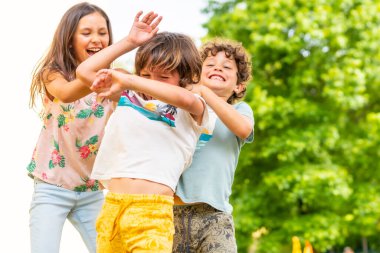 Lifestyle of three brothers smiling and playing together in a park, friends and brothers enjoying as a family, tickling each other