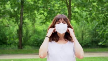 A young woman removing her surgical mask and smiling at the end of the coronavirus pandemic. End of restrictions abroad, happy to be able to breathe well again, covid19, yellow background