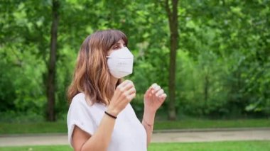 A young woman removing her surgical mask and smiling at the end of the coronavirus pandemic. End of restrictions abroad, happy to be able to breathe well again, covid19, yellow background