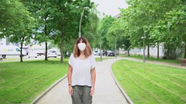 A young woman removing her surgical mask and smiling at the end of the coronavirus pandemic. End of restrictions abroad, happy to be able to breathe well again, covid19, yellow background