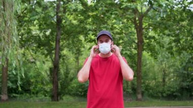 A young man in a red t-shirt removing his surgical mask at the end of the coronavirus pandemic. End of restrictions abroad, happy to be able to breathe well again, covid19