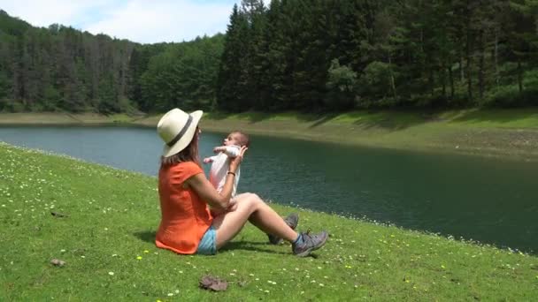 Μια Μητέρα Παίζει Νεογέννητο Γιο Της Μια Λίμνη Που Περιβάλλεται — Αρχείο Βίντεο