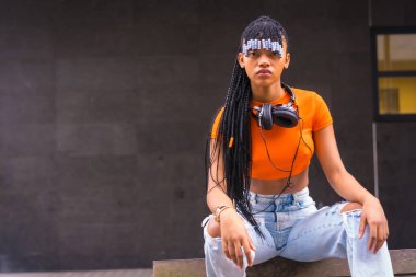 Şehirde örgülü genç bir kapan dansçısıyla yaşam tarzı. Turuncu tişörtlü ve kovboy pantolonlu Afrikalı etnik grubun siyah ırk kızı.