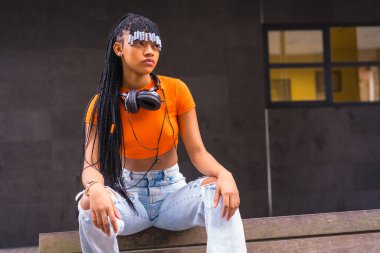 Şehirde örgülü genç bir kapan dansçısıyla yaşam tarzı. Turuncu tişörtlü ve kovboy pantolonlu Afrikalı etnik grubun siyah ırk kızı.