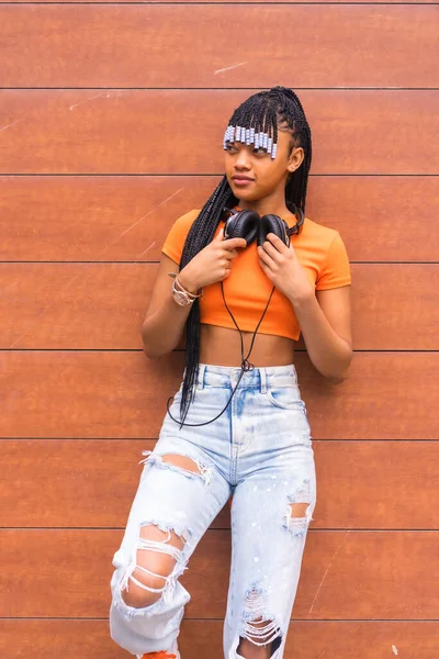 시내에서 댄서와 오렌지 티셔츠를 카우보이 바지를 아프리카 소녀가 배경에 헤드폰을 — 스톡 사진