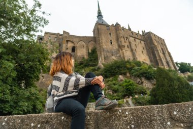 Genç bir turist, Fransa 'nın Normandiya Bölgesi, Manche Bölgesi' ndeki ünlü Mont Saint-Michel Abbey 'i ziyaret ediyor.