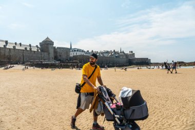 Genç bir baba Fransa 'nın Brittany şehrinde, Grande Plage du Sillon de Saint-Malo' da yazın keyfini çıkarıyor.