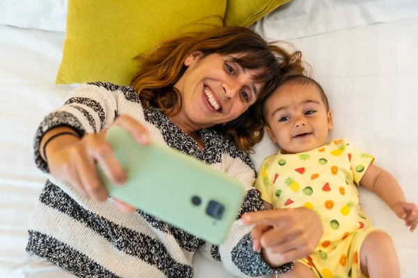 Fiatal Anya Kisbabájával Csinál Egy Szelfit Mobiltelefonnal Ágyon Hálószobájában Család — Stock Fotó