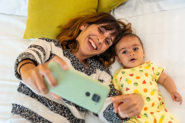 Fiatal Anya Kisbabájával Csinál Egy Szelfit Mobiltelefonnal Ágyon Hálószobájában Család — Stock Fotó