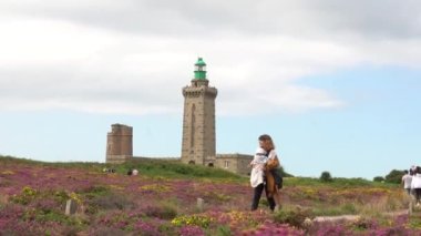 Phare Du Cap Frehel 'de bebeğiyle yürüyen bir anne, Cotes de Armor (Fransa)' da deniz feneridir. Cap Frehel 'in ucundaki 4k video.