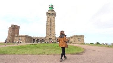 Phare Du Cap Frehel 'de bebeğiyle yürüyen bir anne, Cotes de Armor (Fransa)' da deniz feneridir. Cap Frehel 'in ucundaki 4k video.