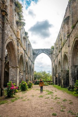 Paimpol 'deki Abbaye de Beauport kilisesinin kalıntılarını ziyaret eden genç bir kadın, Ctes de Armor departmanı, Fransız Brittany. Fransa