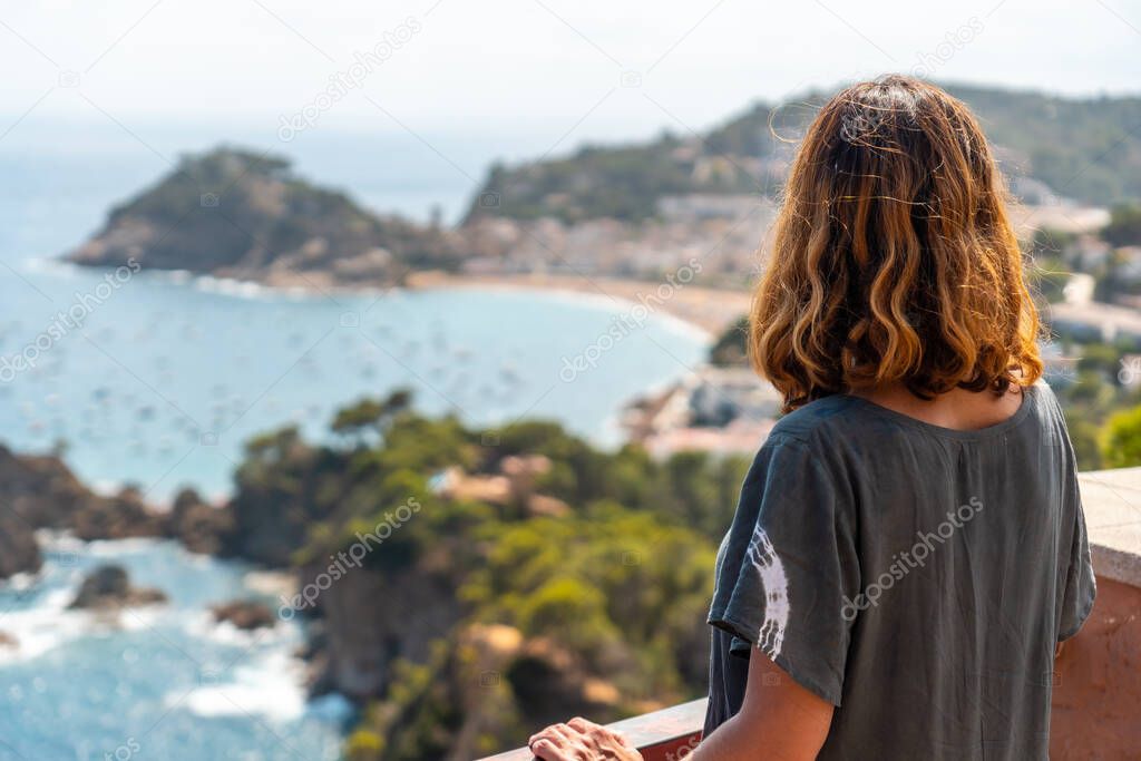 A young tourist looking at Tossa de Mar from the viewpoint, Girona on the Costa Brava of Catalonia in the Mediterranean