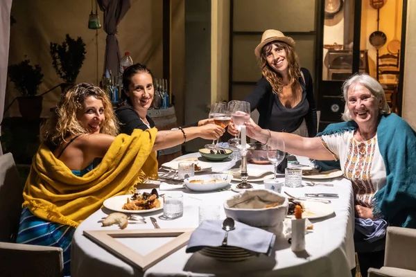 A family and friends at a gala dinner in the evening with beautiful decorations, luxurious dishes and a beautiful tomato salad in the middle