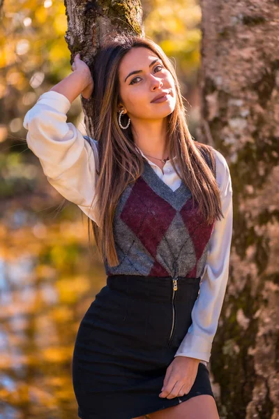 秋天的生活方式 一个年轻的白种人黑发 一个大学女生在一个公园旁边的一棵树与迷人的目光 — 图库照片