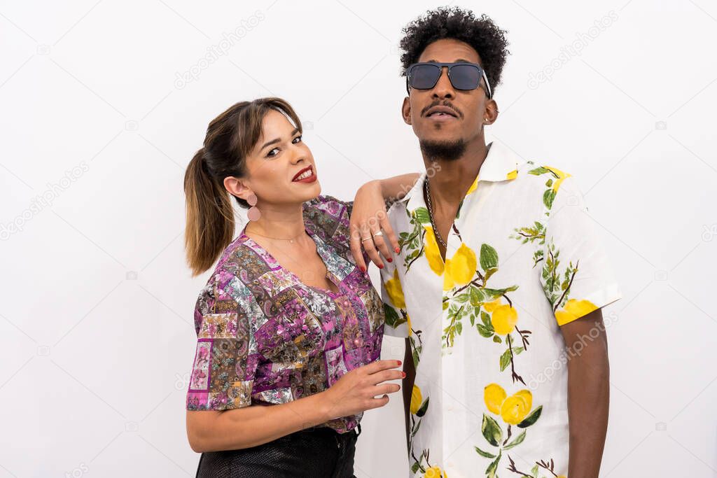 Couple of a black boy and a Caucasian girl on a white background, floral shirts, posed looking at the camera