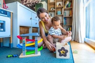 Mutlu anne ve oğul eğitici tahta oyuncaklarla birlikte oynuyorlar, oturma odalarında kaliteli zaman geçiriyorlar.
