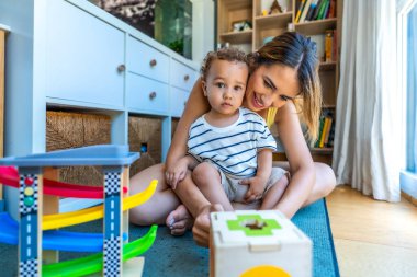 Mutlu anne ve oğul eğitim oyuncaklarıyla oynuyor, rahat bir ev ortamında kaliteli zaman geçiriyorlar.