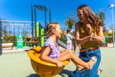 Anne-kız kaynaşıyor, gülüyor ve güneşli bir parkta birlikte oynuyorlar. Çocukluğunda bir anlık mutluluk ve aile eğlencesinin tadını çıkarıyorlar.