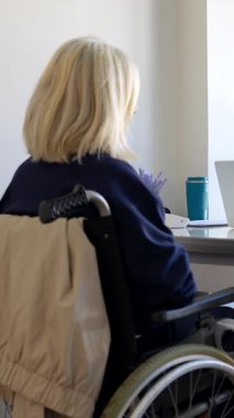 Beyaz önlüklü genç bir kadın doktor, muayenede dizüstü bilgisayar ve tablet kullanarak üst düzey bir kadına tıbbi tavsiyelerde bulunuyor.