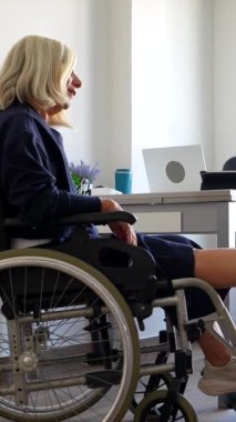 Tekerlekli sandalyedeki yaşlı bir kadının ayağına terapi masajı yapan, modern bir tıp kliniğinde fizik tedavi seansında yardım ve destek sağlayan kadın doktor.