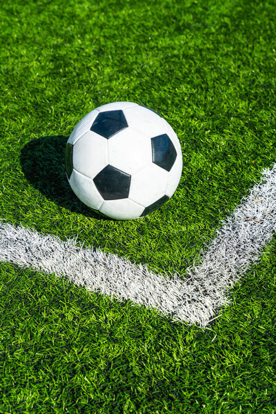 Soccer ball sits on the corner kick line of green artificial turf, ready for play  symbolizing competition, teamwork, training, and the tense moment before a match kickoff