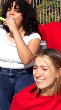 Stadyum tribünlerinden spor müsabakalarını izleyen, tezahürat yapan, alkışlayan ve takımlarının zaferini heyecanla kutlayan hevesli bir grup genç bayan arkadaş ve destekçi.