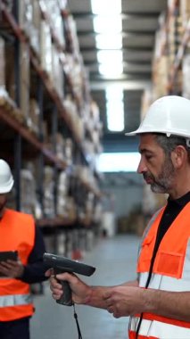 Depo ekibi barkod tarayıcı ve tablet ile envanteri yönetiyor, palet ve raflardaki stokları incelerken endüstriyel bir depolama tesisinde lojistik ve nakliyeleri koordine ediyor.