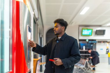 Tren istasyonunda duran genç işadamı, toplu taşıma araçlarıyla yapacağı iş gezisi için otomatik otomattan bilet alıyor.