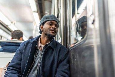 Metroda oturan genç adam, her gün işe gidip gelirken dikkatlice pencereden dışarı bakıyor. Şehir metrosundaki ulaşım sistemindeki yolculuğu yansıtıyor.