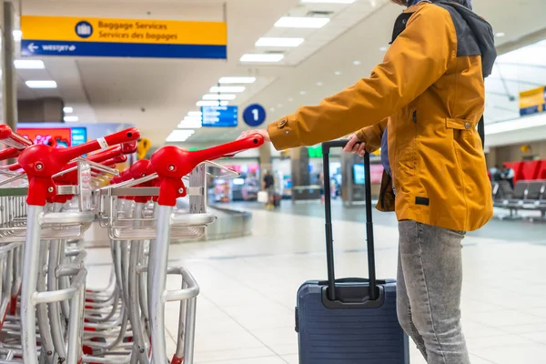 Tourist navigating the airport terminal with a luggage trolley, positioned near the baggage claim area, marking the start of an exciting journey after arrival