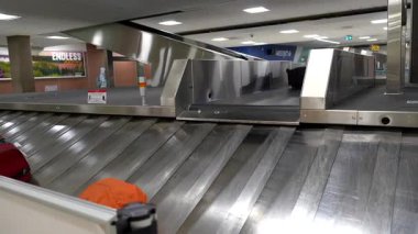 Taşıma bandından çıkan bavullar, dinamik havaalanı bagaj talep ortamını ve varış sürecinde kişisel eşyaları bekleyen yolcuları ortaya çıkarıyor.