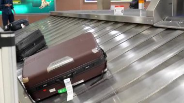 Gezginlerin bavulları ve çantaları havaalanı bagaj atlıkarıncasında sorunsuzca kayıyor, yolcuların uçaktan indikten sonra kişisel eşyalarını almalarını bekliyor.