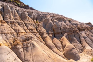 Güneş ışığı, haydutlar olarak bilinen eşsiz jeolojik oluşumları aydınlatır. Davulda tortul kaya katmanları ve erozyon desenleri görülüyor. Alberta. Zaman içinde doğanın gücünün bir kanıtı.