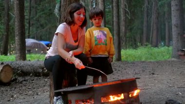 Anne ve oğlu Banff Ulusal Parkı 'ndaki bir kamp ateşinde marşmelov kızartıyorlar. Bu güzel doğal manzaranın ortasında kamp gezisinin tadını çıkarıyorlar.