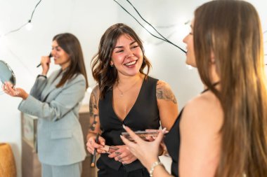 Genç bayan arkadaşlar makyaj yapıyor, saç şekillendiriyor, yeni yıl partisine hazırlanırken gülüyor ve kaynaşıyorlar. Güzelliğin, eğlencenin ve beklentinin tadını çıkarıyorlar.