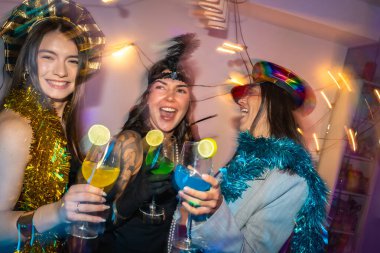 Şenlikli parti şapkaları takan, renkli limonlu kokteyller içen, neşeli, enerjik yeni yıl arifesinde ya da kostüm partisinde gülen ve dans eden farklı kadınlar.