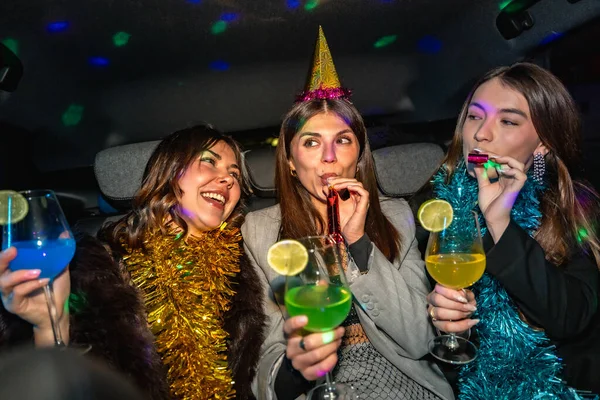 Süslü bir parti arabasında, renkli kokteyller ve kahkahalarla kutlama yapan genç kadınlar.