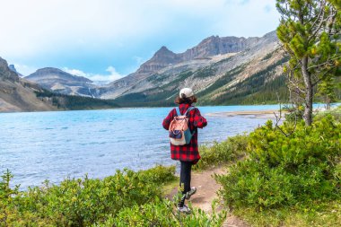 Sırt çantalı kadın turist, turkuaz yay gölü kıyısında yürüyor. Arka planda ise Banff Ulusal Parkı, Alberta, Kanada 'da güneşli bir yaz günü.
