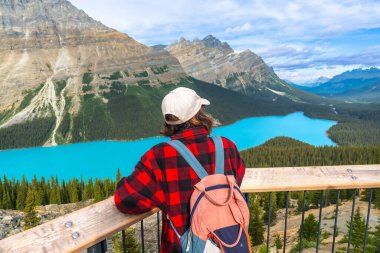 Yaz tatili boyunca Banff Ulusal Parkı, Alberta, Kanada 'da Kanadalı kayalıkların nefes kesen manzarasının keyfini sürerken Peyton Gölü' nün göz kamaştırıcı turkuaz rengine hayran olan genç yürüyüşçü