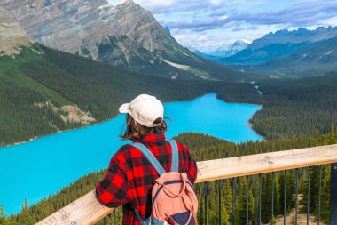 Genç yürüyüşçü, Banff Ulusal Parkı, Kanada kayalıkları, Alberta, Kanada 'da güneşli bir günde Turkuaz Peyton Gölü' nün manzarasının tadını çıkarıyor.