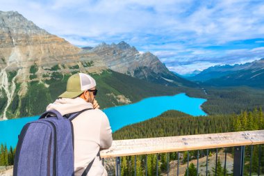 Sırt çantalı turist, güzel güneşli bir günde Turkuaz Peyton Gölü 'nün ve Banff Ulusal Parkı, Alberta' daki Kanada kayalıklarının nefes kesici manzarasının keyfini çıkarıyor.