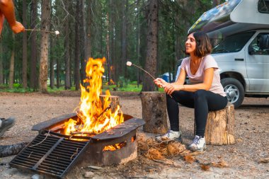 Turistler Banff Ulusal Parkı 'ndaki kamp arabalarının yanında marşmelov kızartıyorlar. Kanada kayalıkları, Alberta. Doğada dinlendirici bir akşamın tadını çıkarıyorlar.