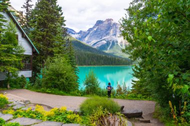 Sırt çantalı turist, zengin ormanlarla çevrili zümrüt gölünün turkuaz sularının ve Banff Milli Parkı, Alberta 'daki görkemli Kanada kayalarının nefes kesici manzarasının tadını çıkarıyor.