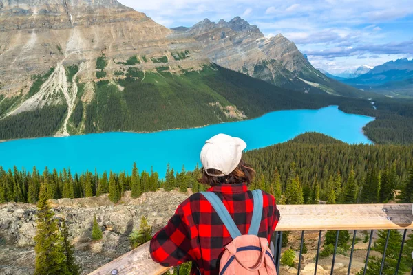 Sırt çantalı turist, Banff Milli Parkı 'ndaki görkemli Kanada kayalıklarıyla çevrili Peyton Gölü' ndeki canlı turkuaz suların tadını çıkarıyor.
