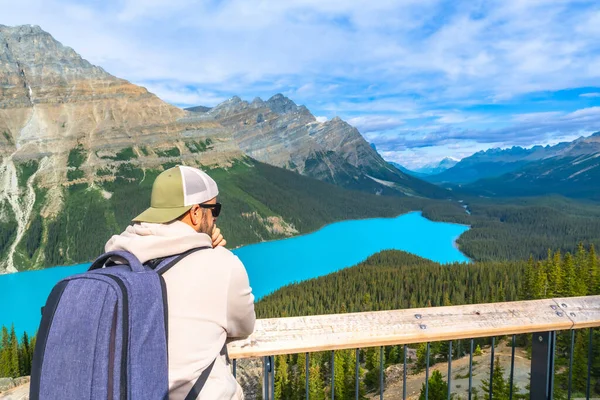 Sırt çantalı turist, güzel güneşli bir günde Turkuaz Peyton Gölü 'nün ve Banff Ulusal Parkı, Alberta' daki Kanada kayalıklarının nefes kesici manzarasının keyfini çıkarıyor.