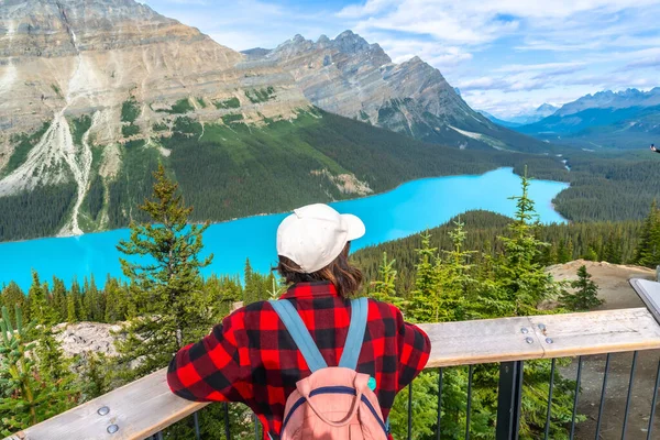 Sırt çantalı kadın turist, Banff Ulusal Parkı, Alberta 'daki görkemli Kanada kayalıkları tarafından çerçevelenmiş, Peyton Gölü' nün büyüleyici turkuaz sularına hayran.